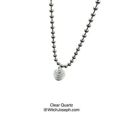Silver tone ball chain necklace with a clear quartz chip in cage pendant on a gray background