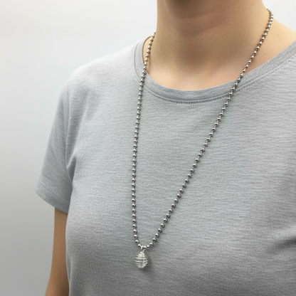Person wearing a silver tone ball chain necklace with a clear quartz chip in cage pendant on a plain background