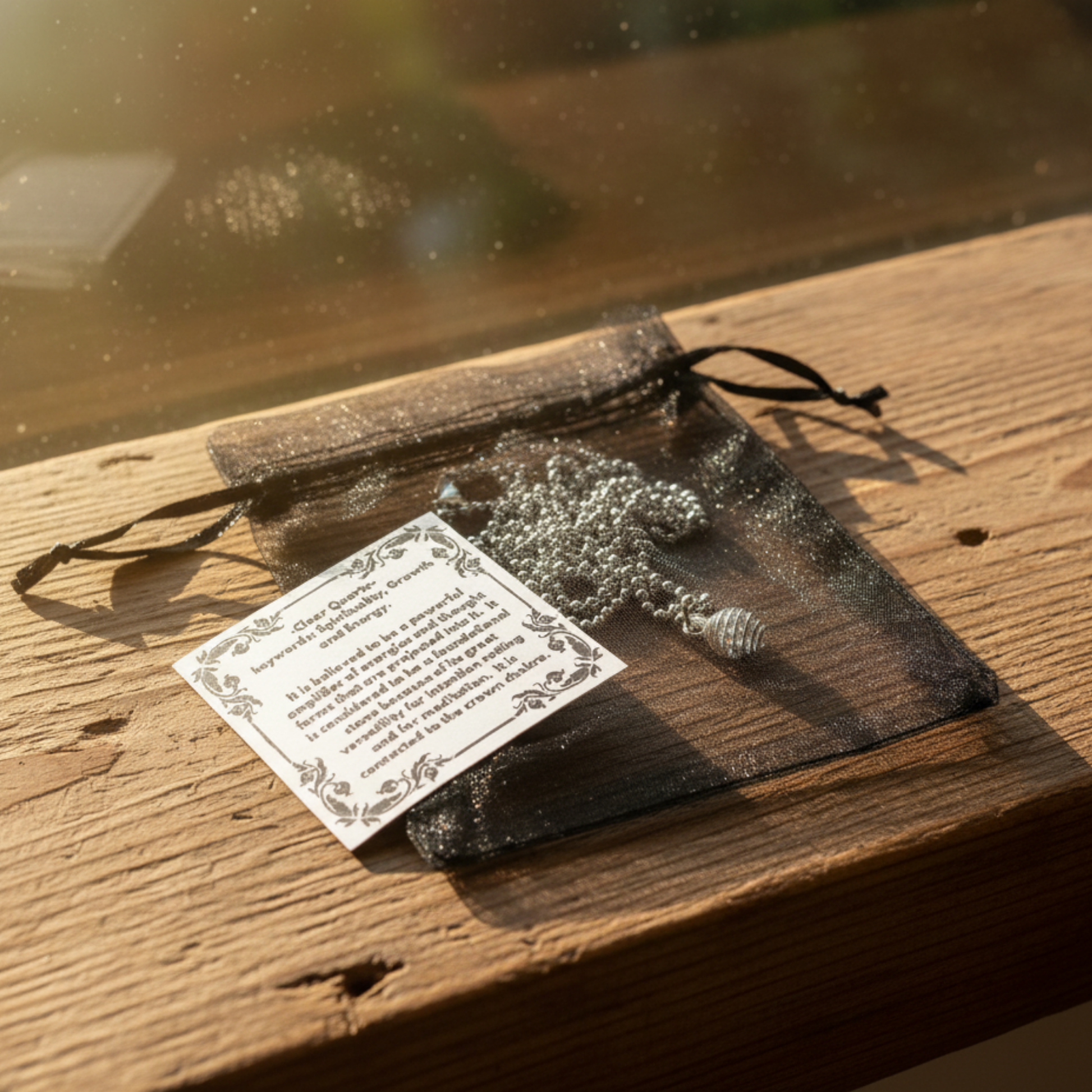 Silver tone necklace with a black organza bag with an information sticker on a wooden surface