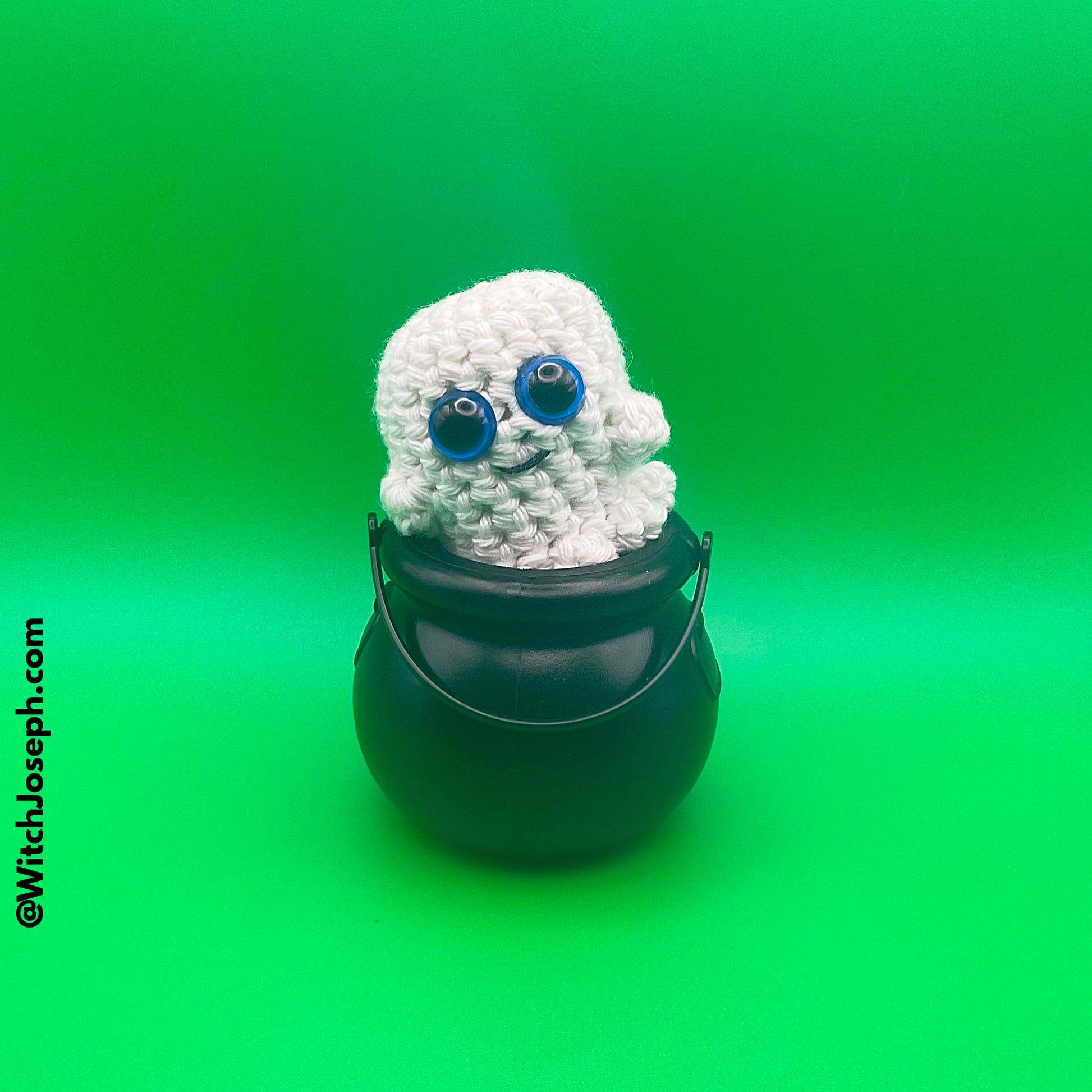 White knitted ghost with blue eyes in a black cauldron on a green background with the Witch Joseph URL