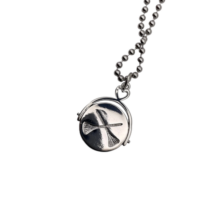 Silver tone necklace with a circular crossed brooms pendant on a white background.
