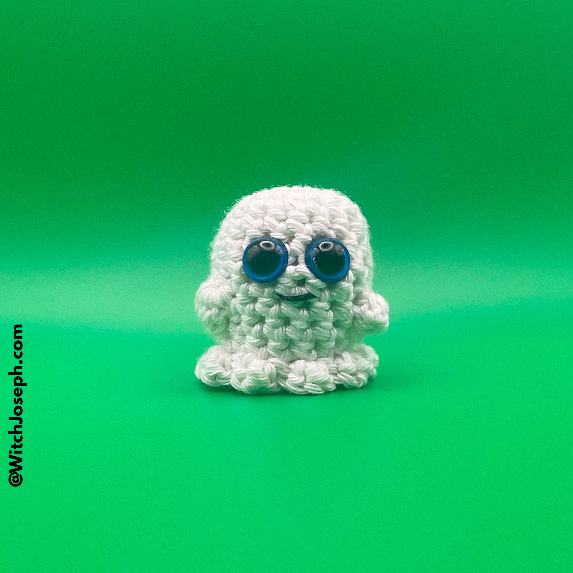 White crochet ghost with blue eyes on a green background with the Witch Joseph URL