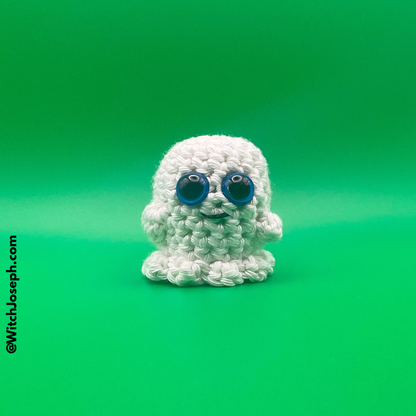 White crochet ghost with blue eyes on a green background with the Witch Joseph URL