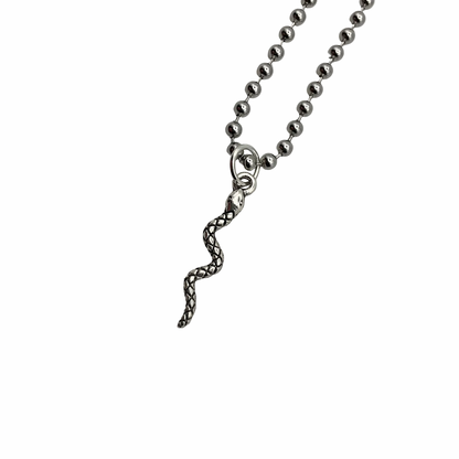 Silver tone delicate snake pendant on a ball chain against a white background