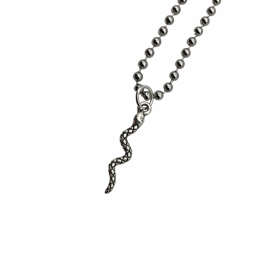 Silver tone delicate snake pendant on a ball chain against a white background