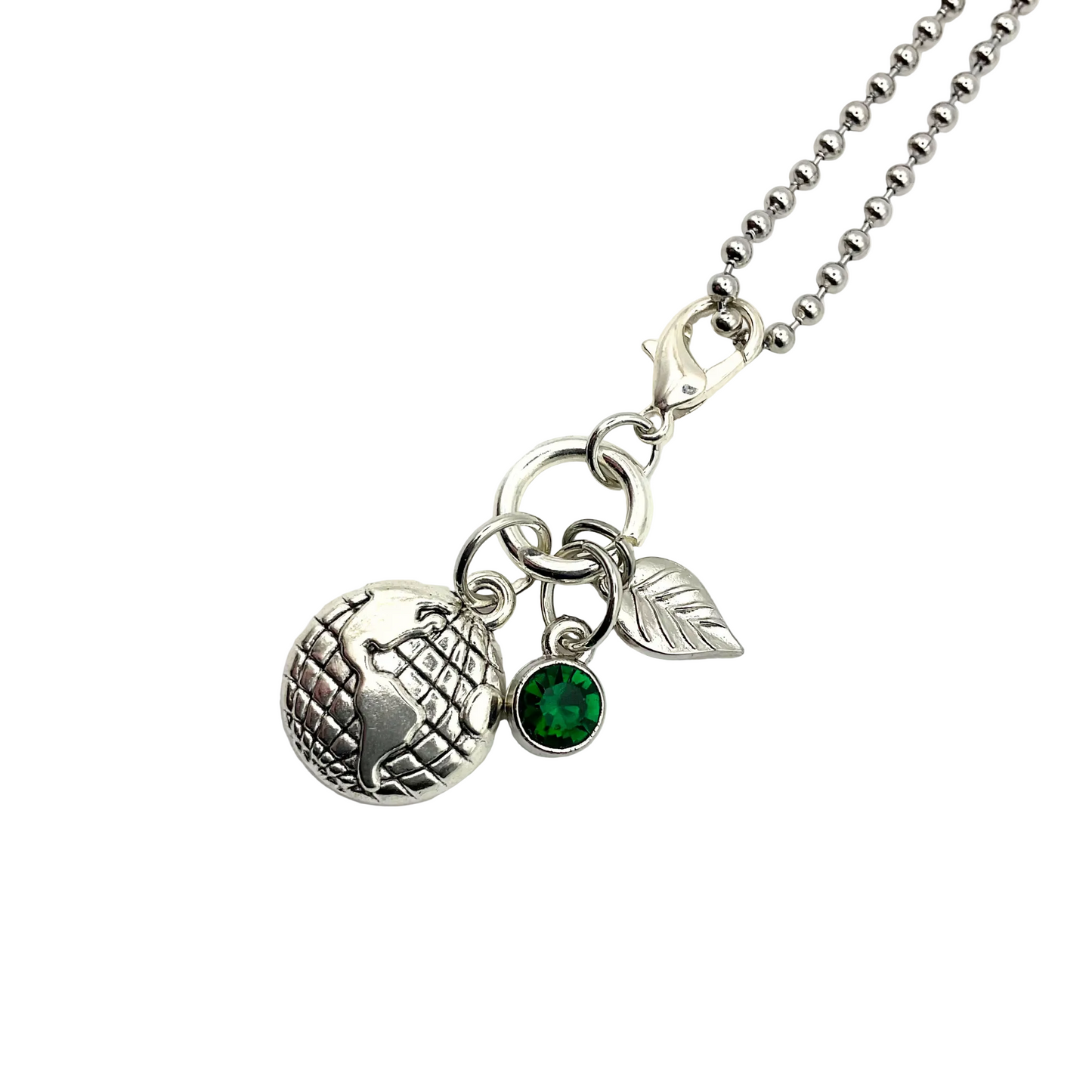 Necklace with earth globe, silver tone leaf, and green crystal charms on a white background
