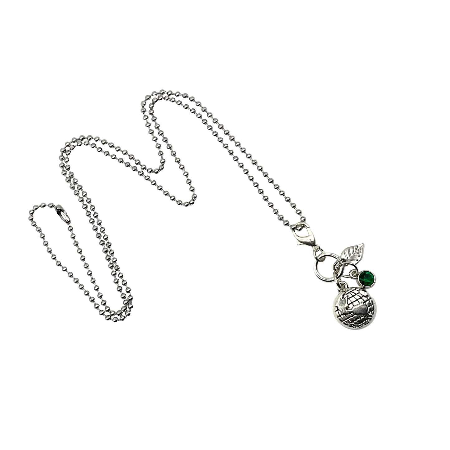 Silver tone earth day necklace with three charms…an earth globe, a silver tone leaf and a green crystal on a white background.