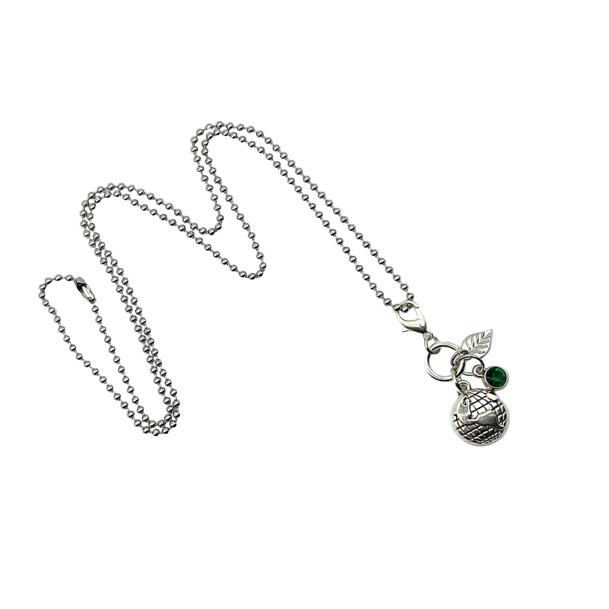 Silver tone earth day necklace with three charms…an earth globe, a silver tone leaf and a green crystal on a white background.