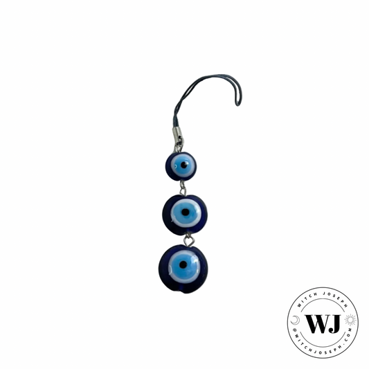 Evil eye charm with three blue and white circular “evil eye” designs on a white background, branded with 'WJ'.