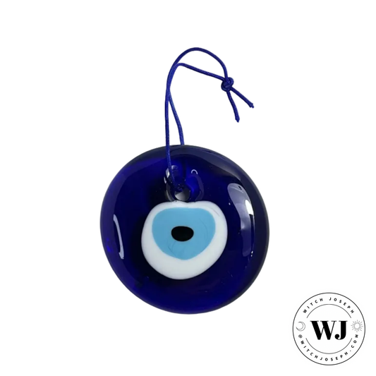 Blue evil eye ornament with a white center on a white background, featuring the brand 'Witch Joseph’