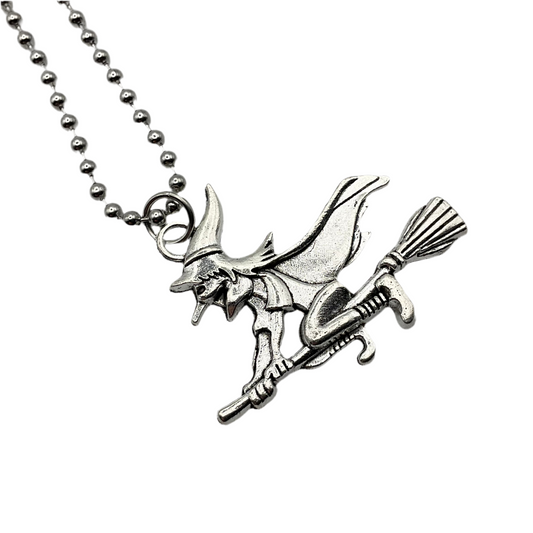 Silver tone witch on broomstick pendant on a ball chain against a white background