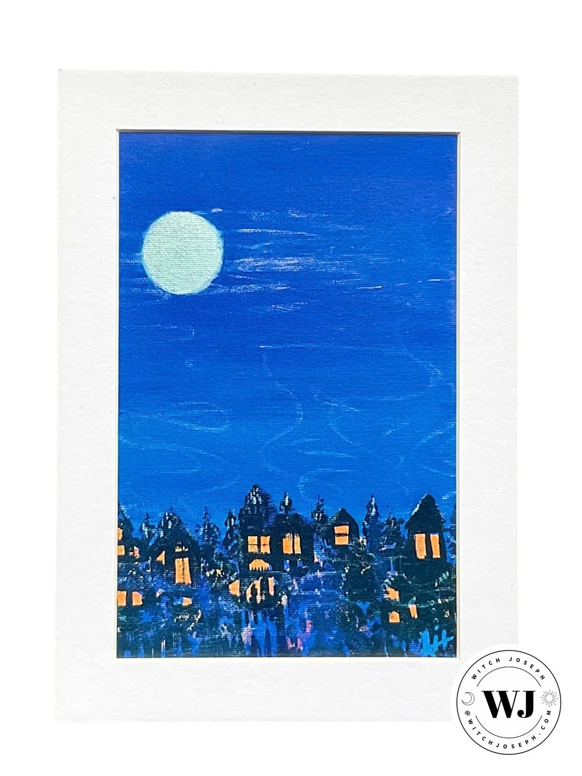 A matted art print featuring a textured blue painting of a village at night under a large pale moon, shown against a white background with a circular 'WJ' Witch Joseph watermark in the lower right.