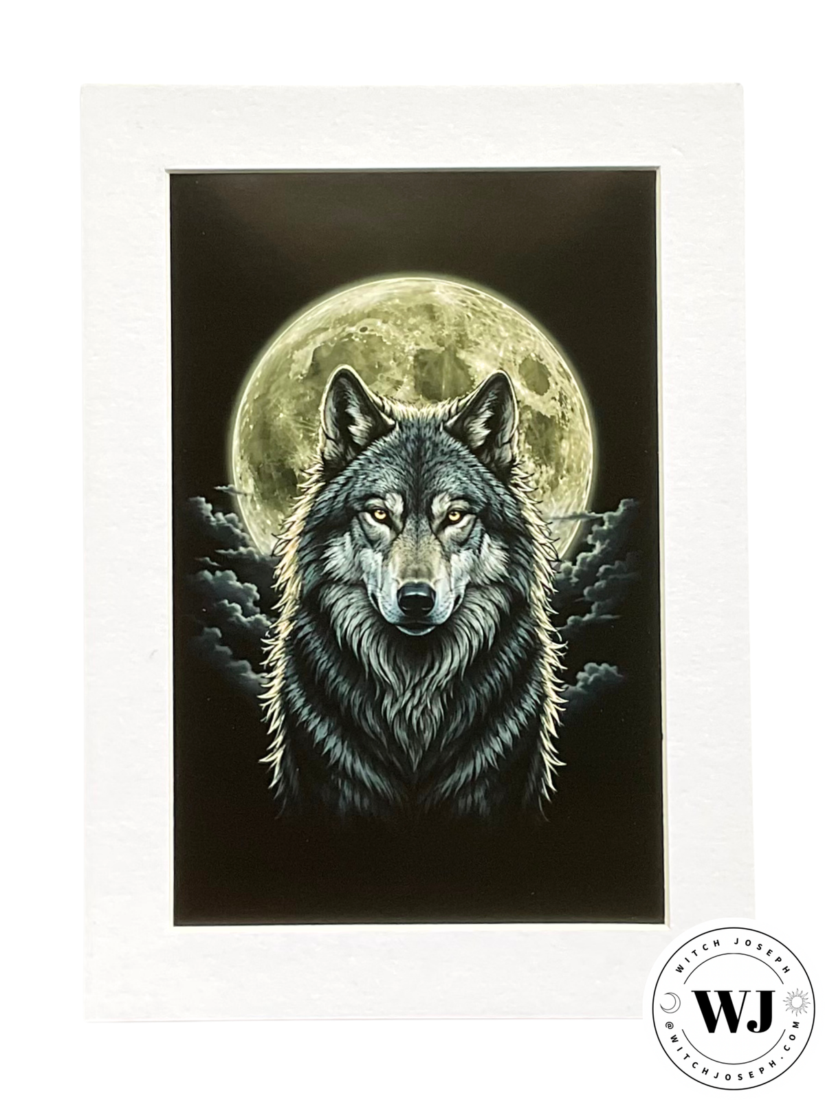 A matted art print featuring a detailed illustration of a wolf with glowing eyes set against a large full moon and dark clouds. The print is mounted in a white mat, with a circular 'WJ' Witch Joseph logo in the bottom right corner.