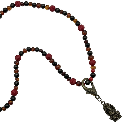 Necklace with multicolored Amber Jet and Coral beads and a decorative clasp with a bronze tone Ganesha Pendant on a white background