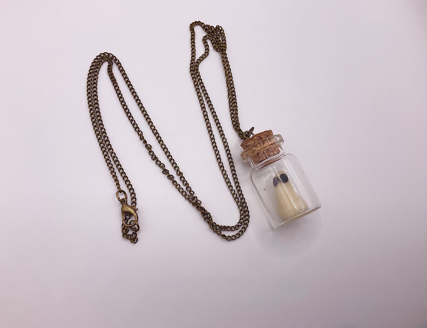 Necklace with a glass bottle with a glow in the dark ghost inside pendant on a white background