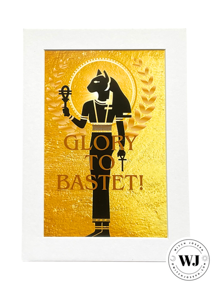 An art print featuring a black silhouette of Bastet on a textured gold background with the text 'GLORY TO BASTET!'. The print has a wide white border and is shown against a plain white background, with a circular 'WJ Witch Joseph' watermark in the bottom right corner.
