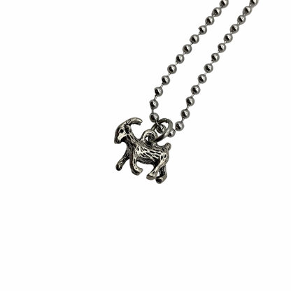 Silver tone goat pendant on a ball chain against a white background
