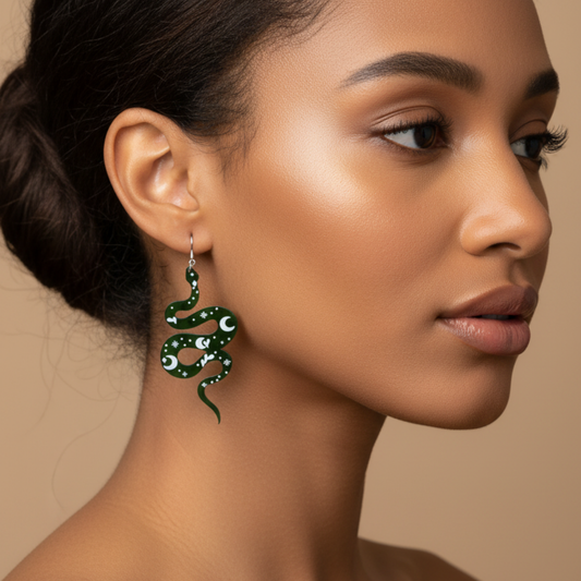Woman wearing a green snake-shaped earring that has a lunar design on a beige background
