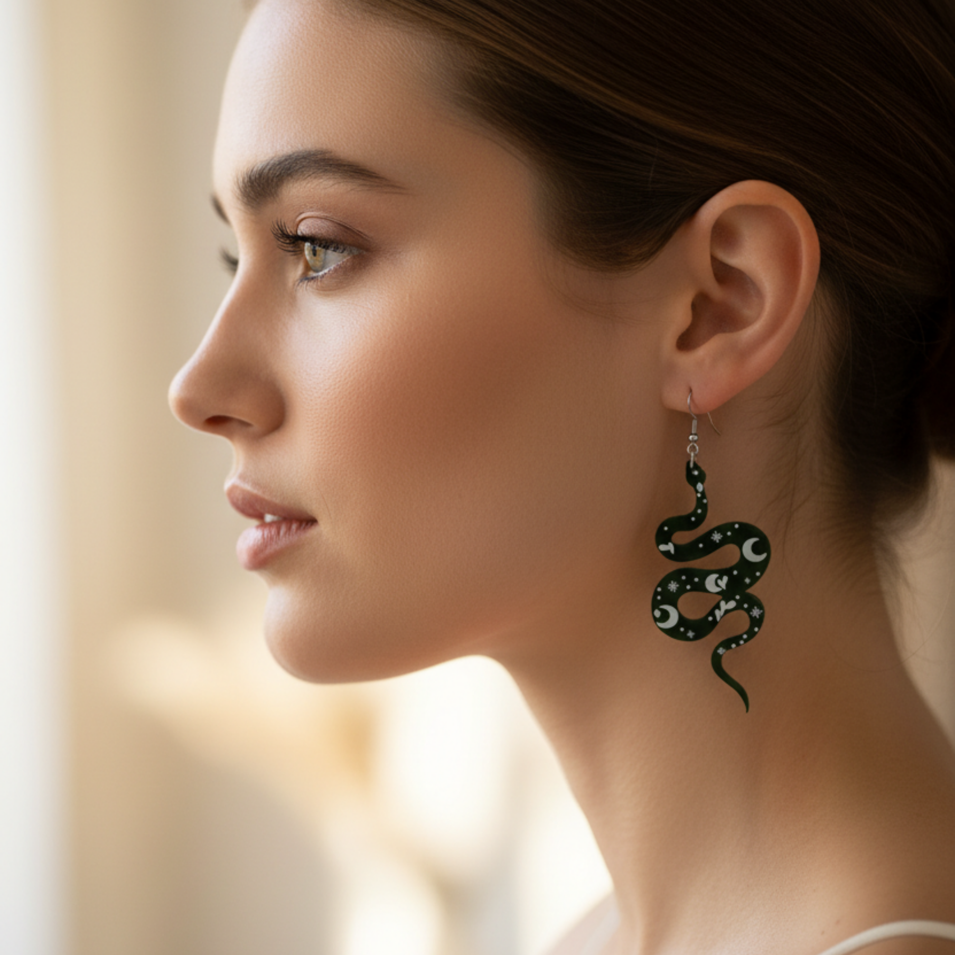 Woman wearing a snake-shaped earring with lunar designs against a portrait style blurred background