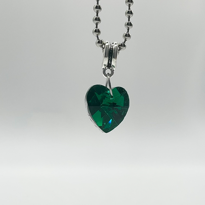 Green heart-shaped crystal pendant on a silver tone ball chain against a white background