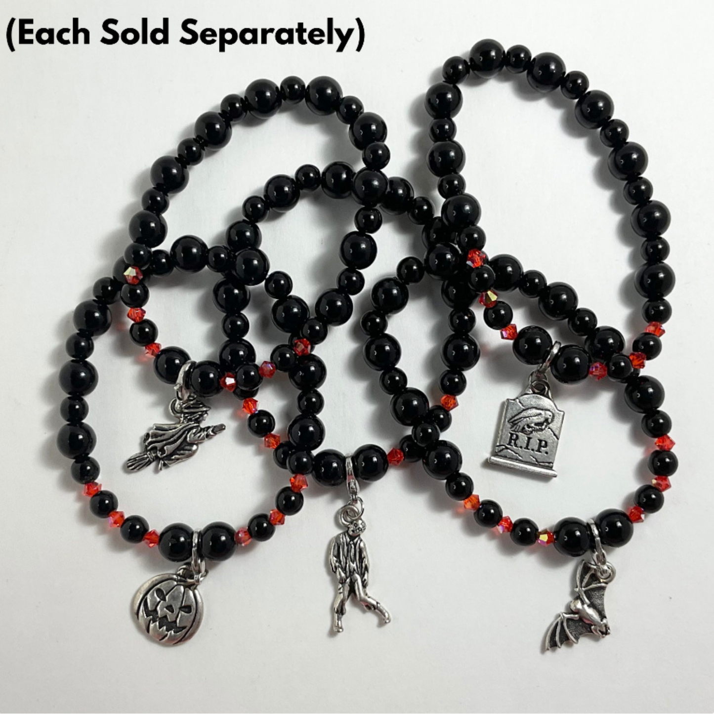 Black beaded stretch bracelets with orange crystal accents with various halloween charms on a white background…with text “each sold separately”