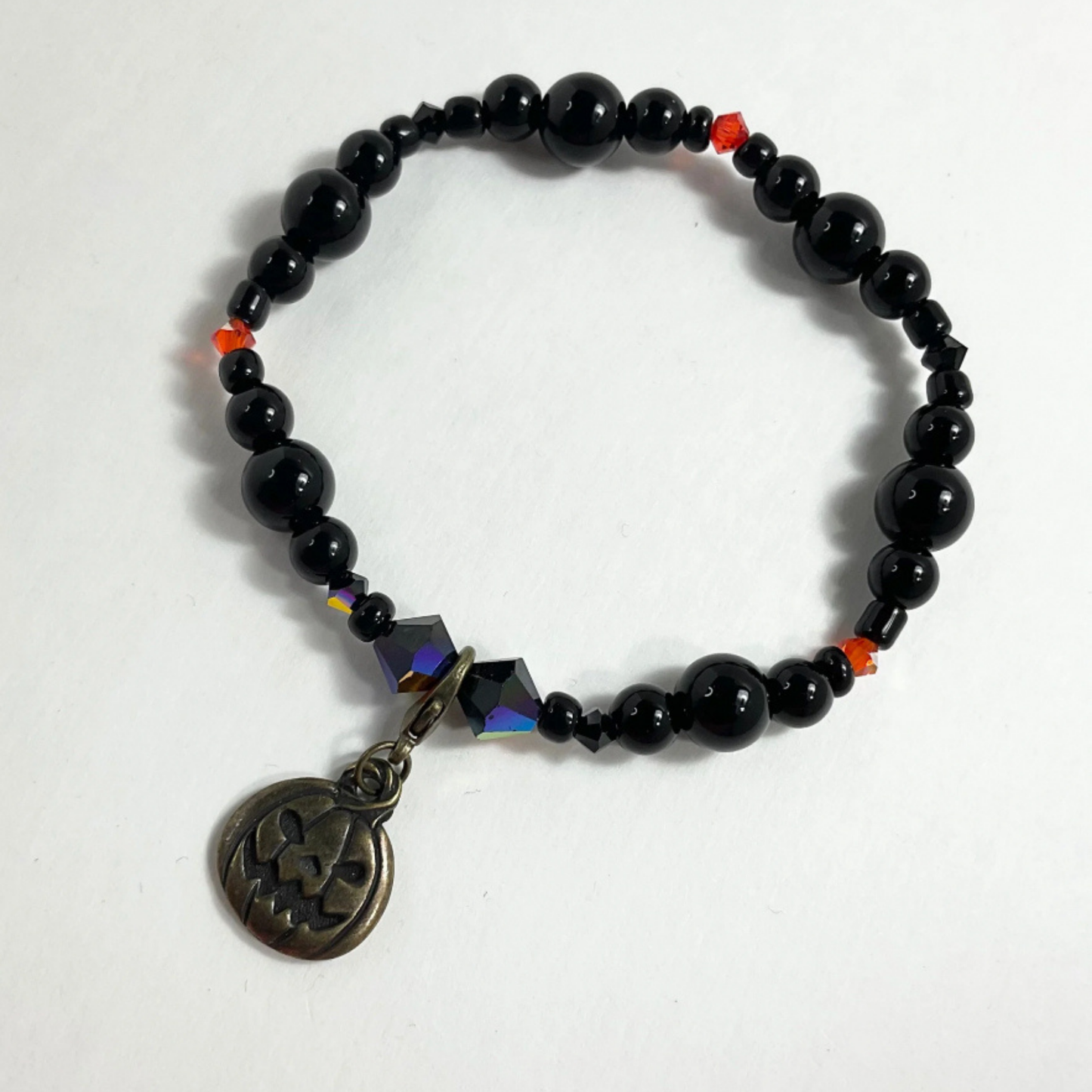 Black beaded bracelet with a jack o lantern pendant on a white background