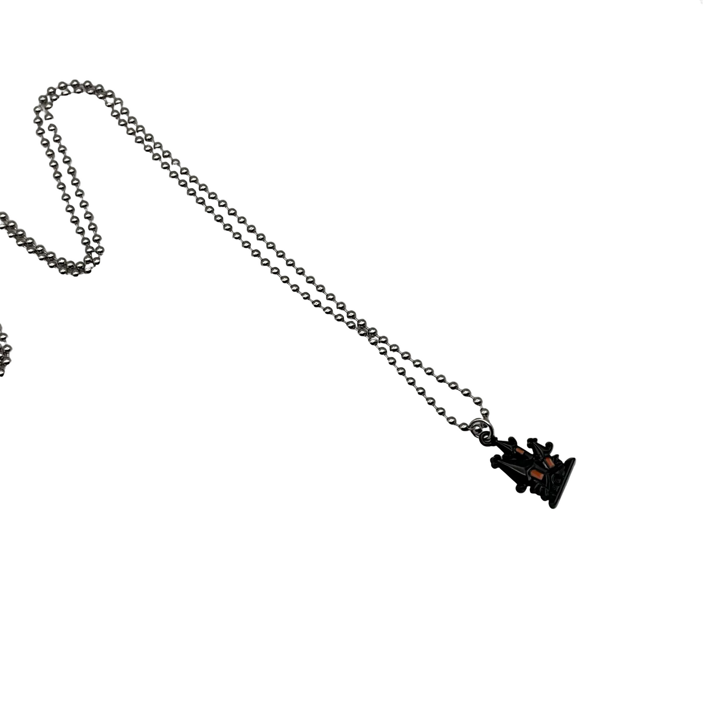 Charm Necklace with a small black Haunted House pendant with orange accents on a white background
