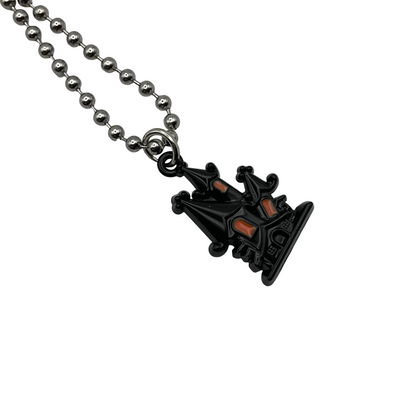 Black Haunted House pendant with orange accents on a silver tone ball chain against a white background