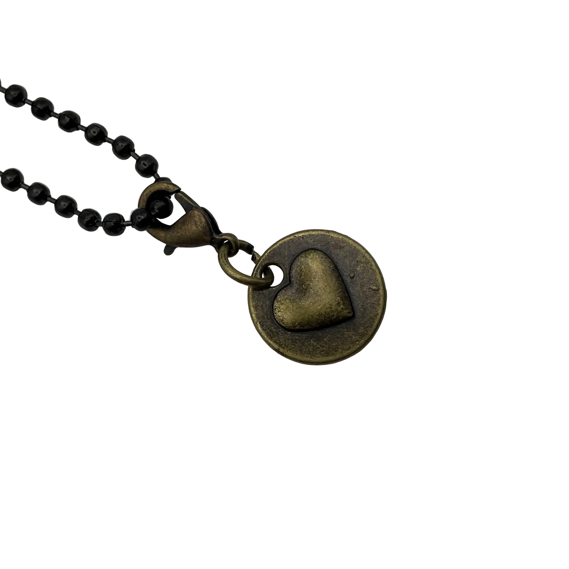 Bronze heart on a circle shaped pendant, with “love” written on the reverse, on a black ball chain against a white background