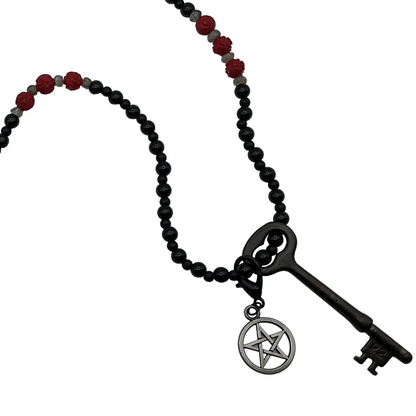 Hekate Necklace with black beads, red coral stones, and a vintage key pendant with pentacle on a white background