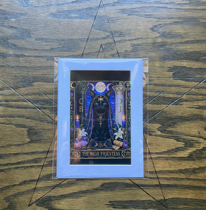 A matted art print featuring a tarot card illustration of 'The High Priestess' with a black cat under a full moon, displayed on a wooden surface.