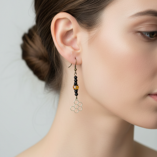 A woman’s face from the side showing her wearing the honeycomb earring which is black and golden color with a gold tone honeycomb dangle 