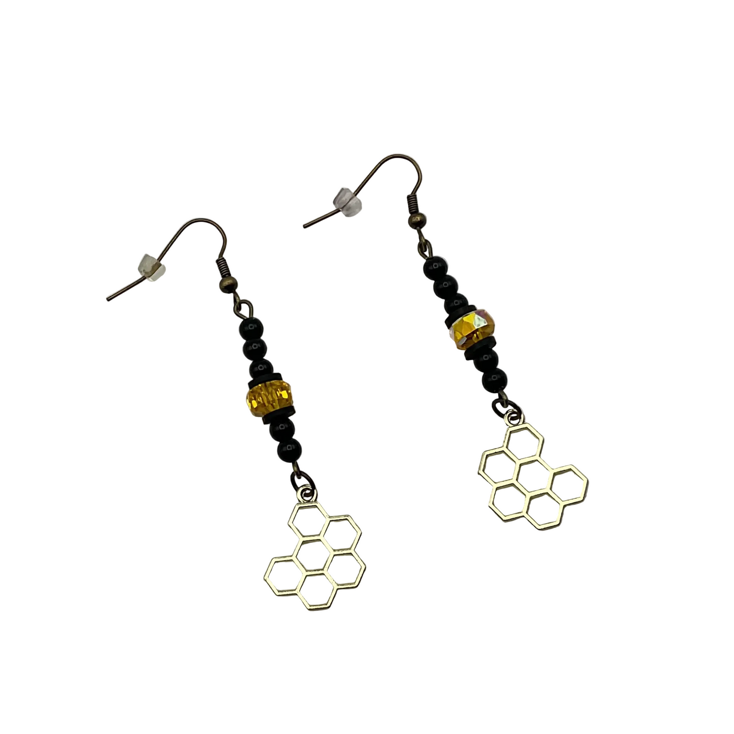 Pair of earrings with dangling honeycomb designs with black beads and a sparkly golden tone crystal bead displayed on a white background