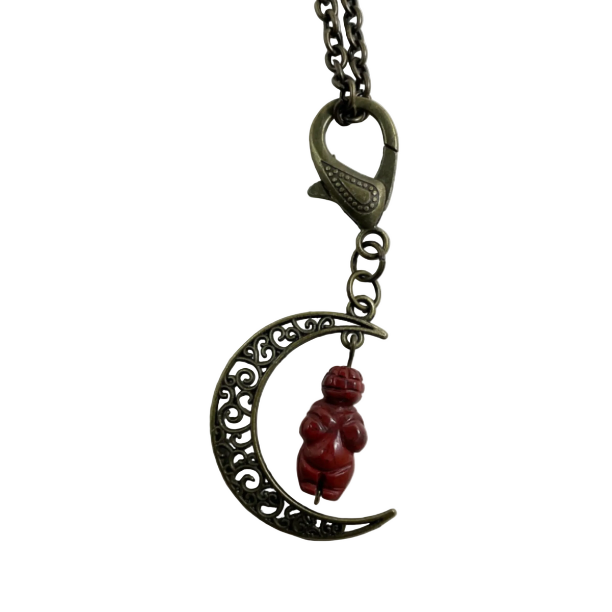 A bronze filigree crescent moon pendant necklace featuring a small red jasper carved Goddess figurine charm, shown on a plain white background.