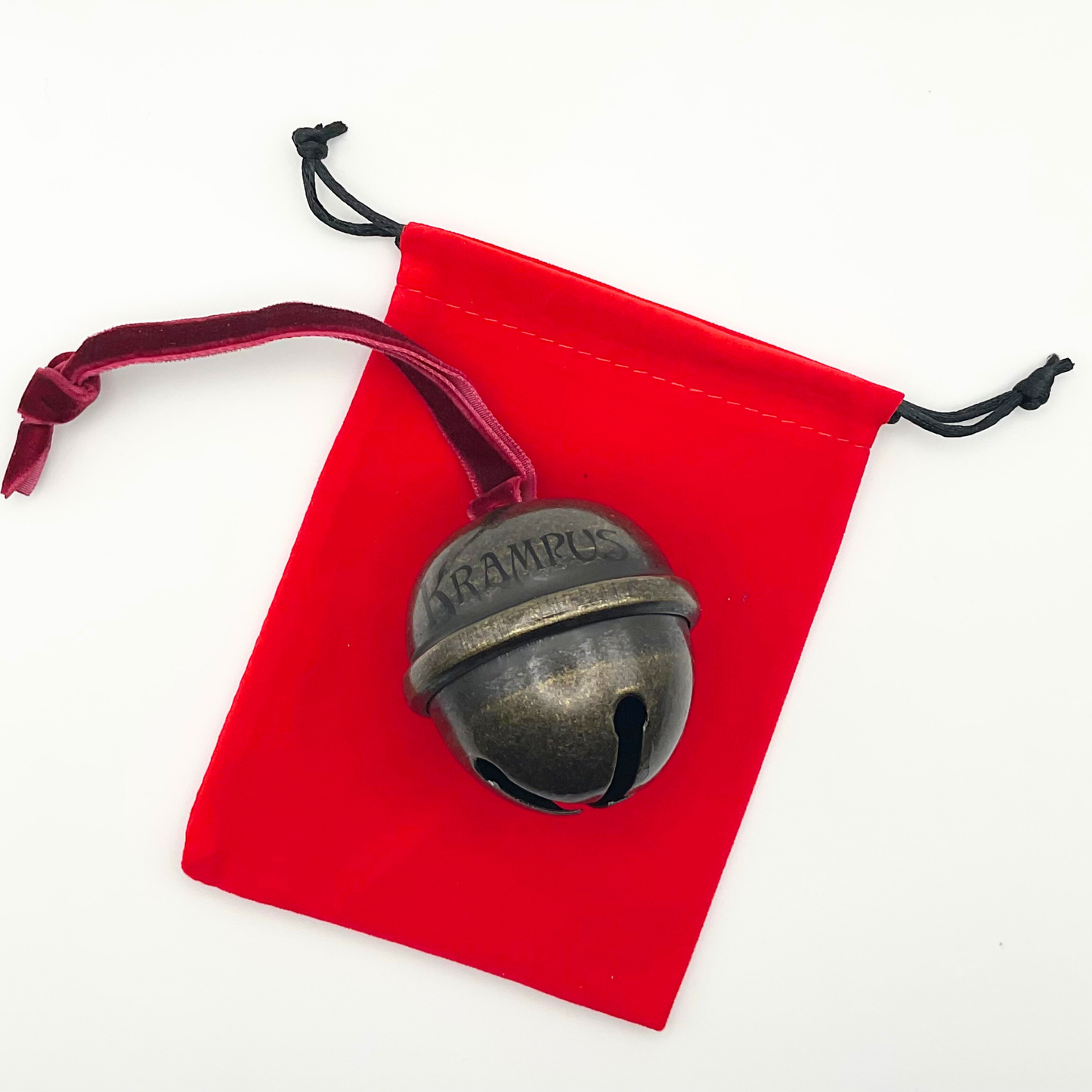 Bronze bell with 'Krampus' engraving on a red drawstring bag