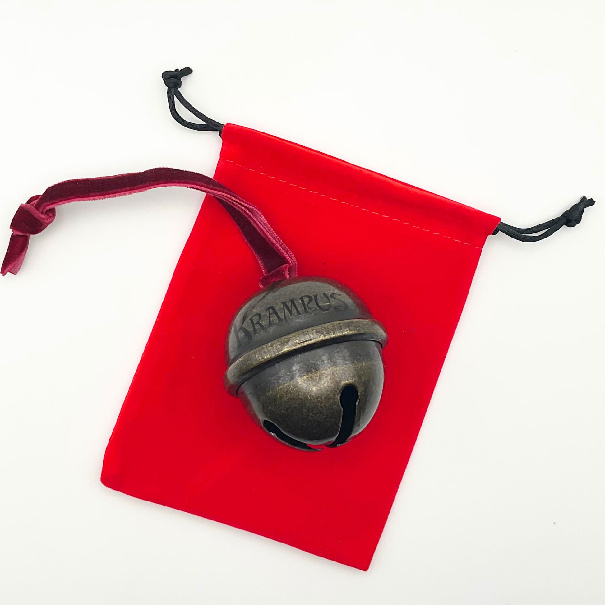 Bronze bell with 'Krampus' engraving on a red drawstring bag