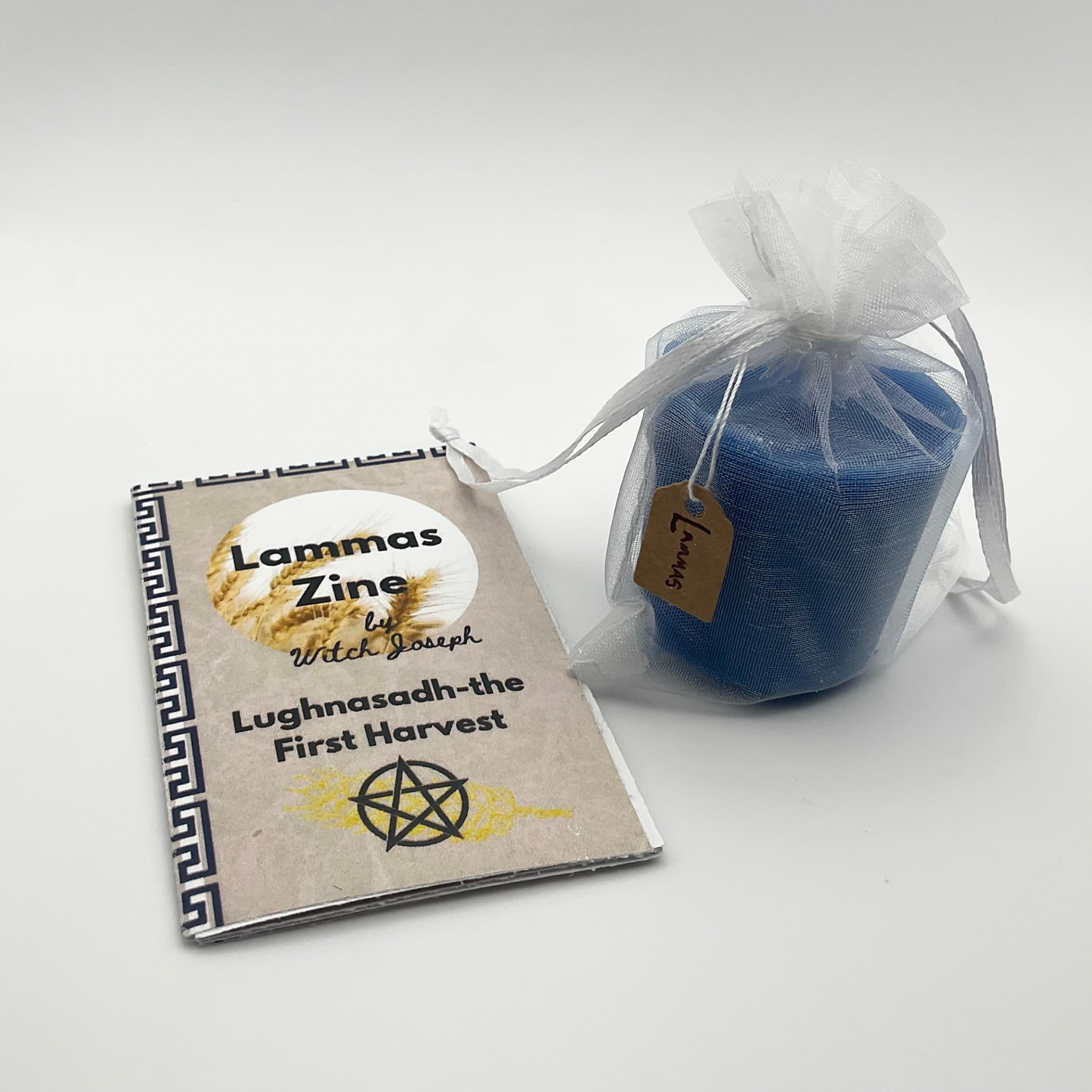 Lammas zine and blue Lammas candle in a sheer bag on a white background