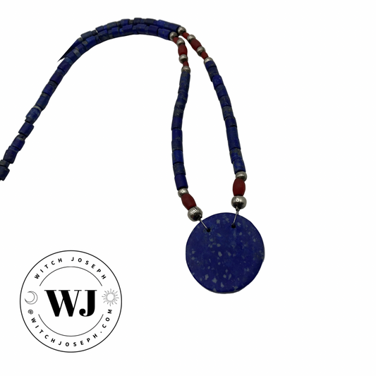 Necklace with blue Lapis lazuli disc, lapis lazuli beads and red and silver tone accent beads displayed on a white background, featuring the WJ logo.