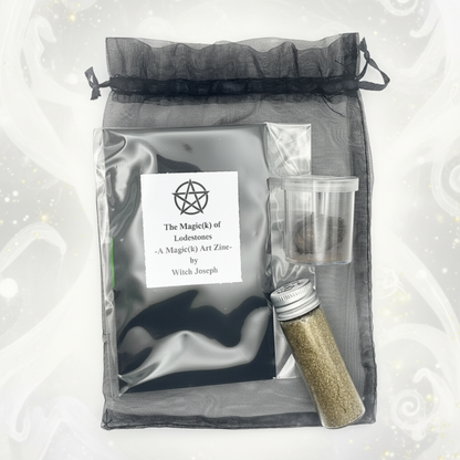 Lodestone Kit on black organza bah showing the Zine, the Lodestone and the magnetic sand against a white background.