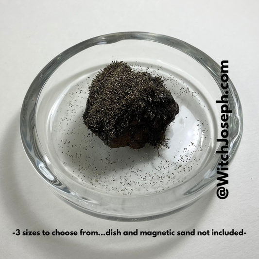 Lodestone in a dish with gold magnetic sand on a white background with the Witch Joseph URL