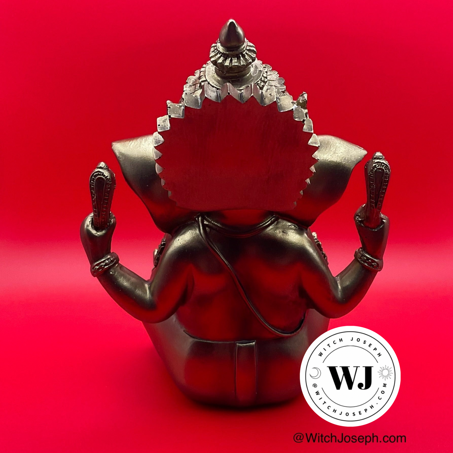 Metallic gold tone Ganesha figurine with intricate design displayed on a red background, featuring the brand 'WJ' Witch Joseph