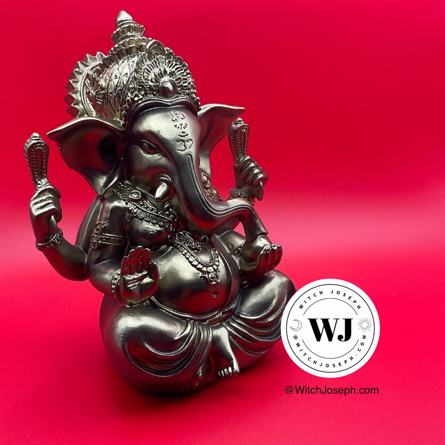 Gold tone Ganesha statue on a red background with Witch Joseph logo and url