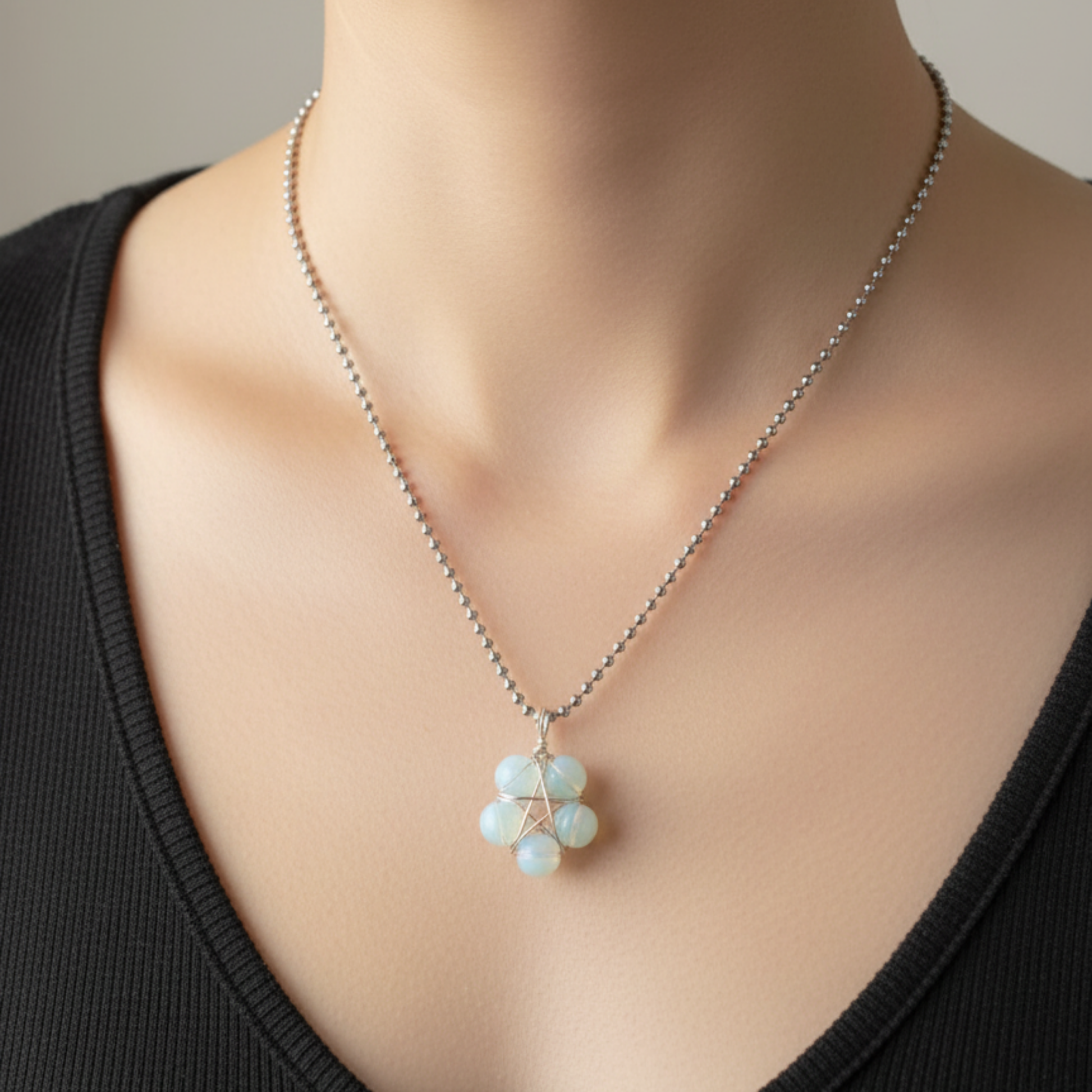 Necklace with a opalite pentagram pendant displayed on a person wearing a black top.