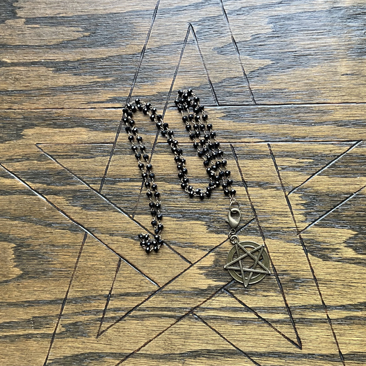 Sparkle bead Necklace with a pentagram pendant displayed on a wooden surface with a pentagram etched onto it