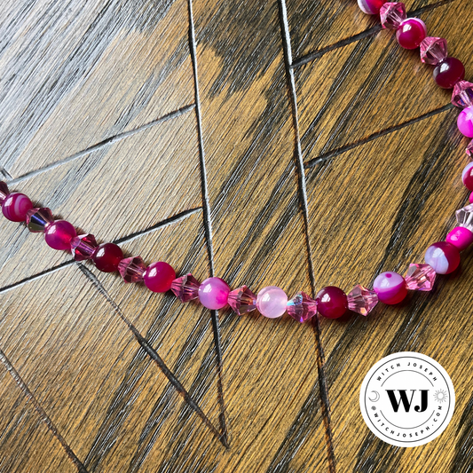 a close up image of the beads on the Pink Agate with Pink Crystals Choker…shown on rustic wood surface and with the Witch Joseph Logo