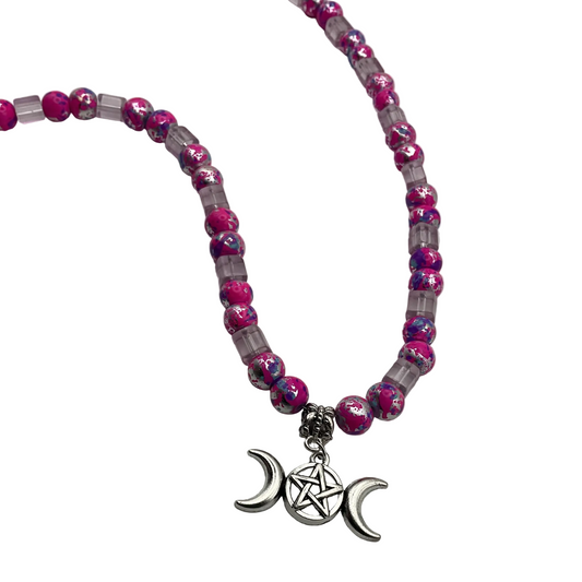 Beaded necklace with pink beads and a silver tone triple goddess pentacle charm on a white background.