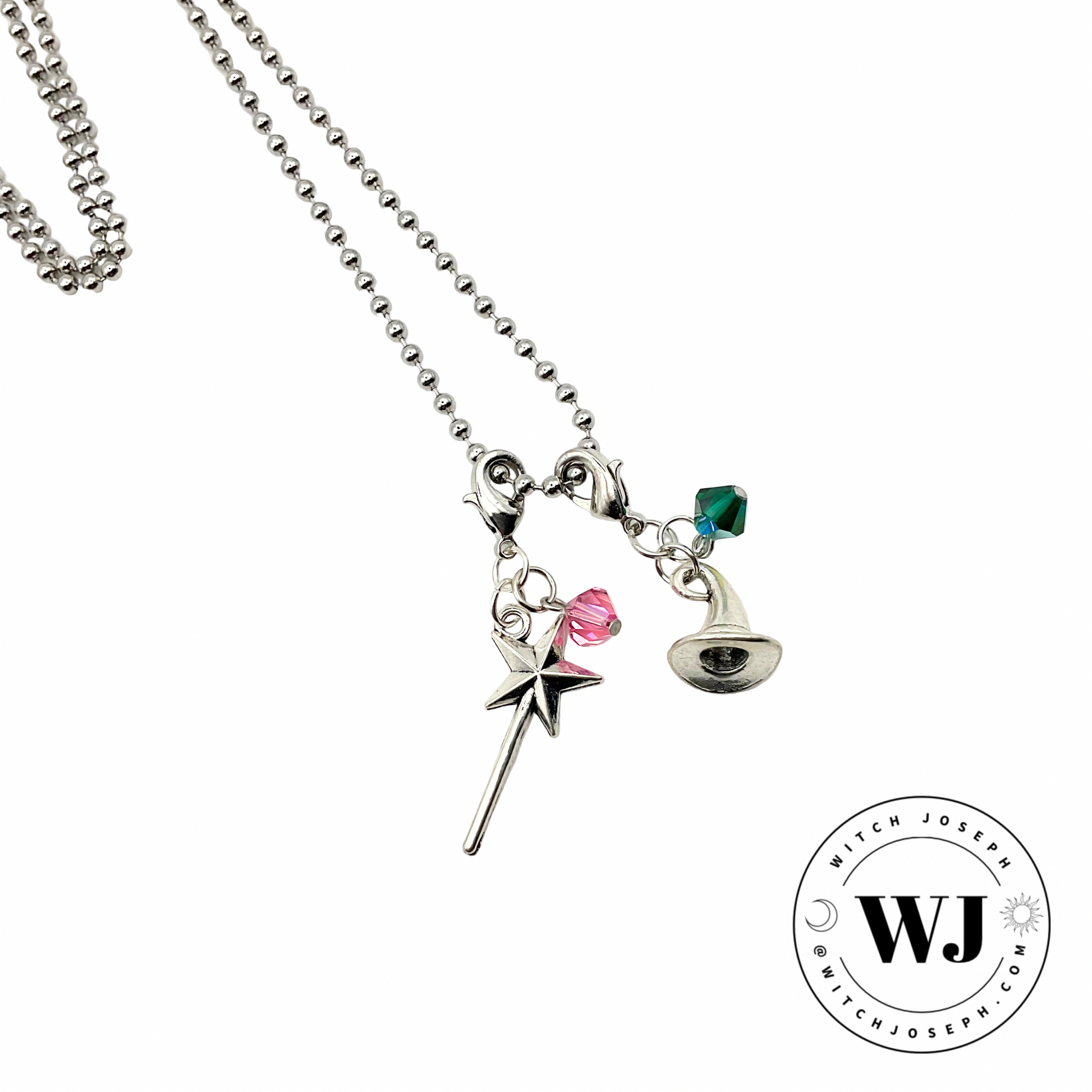 A Charm necklace with a pink crystal and magic wand and a green crystal and witch hat on a ball chain displayed against a white background with the Witch Joseph logo