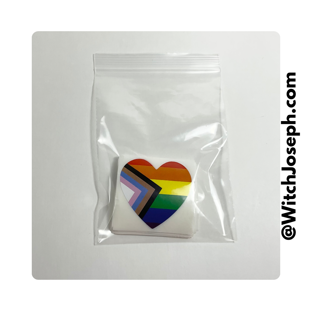 Heart-shaped rainbow flag stickers in a clear plastic bag on a white background