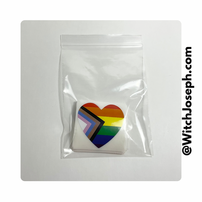Heart-shaped rainbow flag stickers in a clear plastic bag on a white background