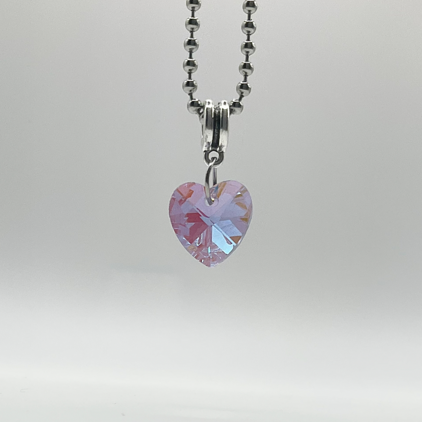 Charm Necklace with a purple tinted heart-shaped crystal pendant on a gray background